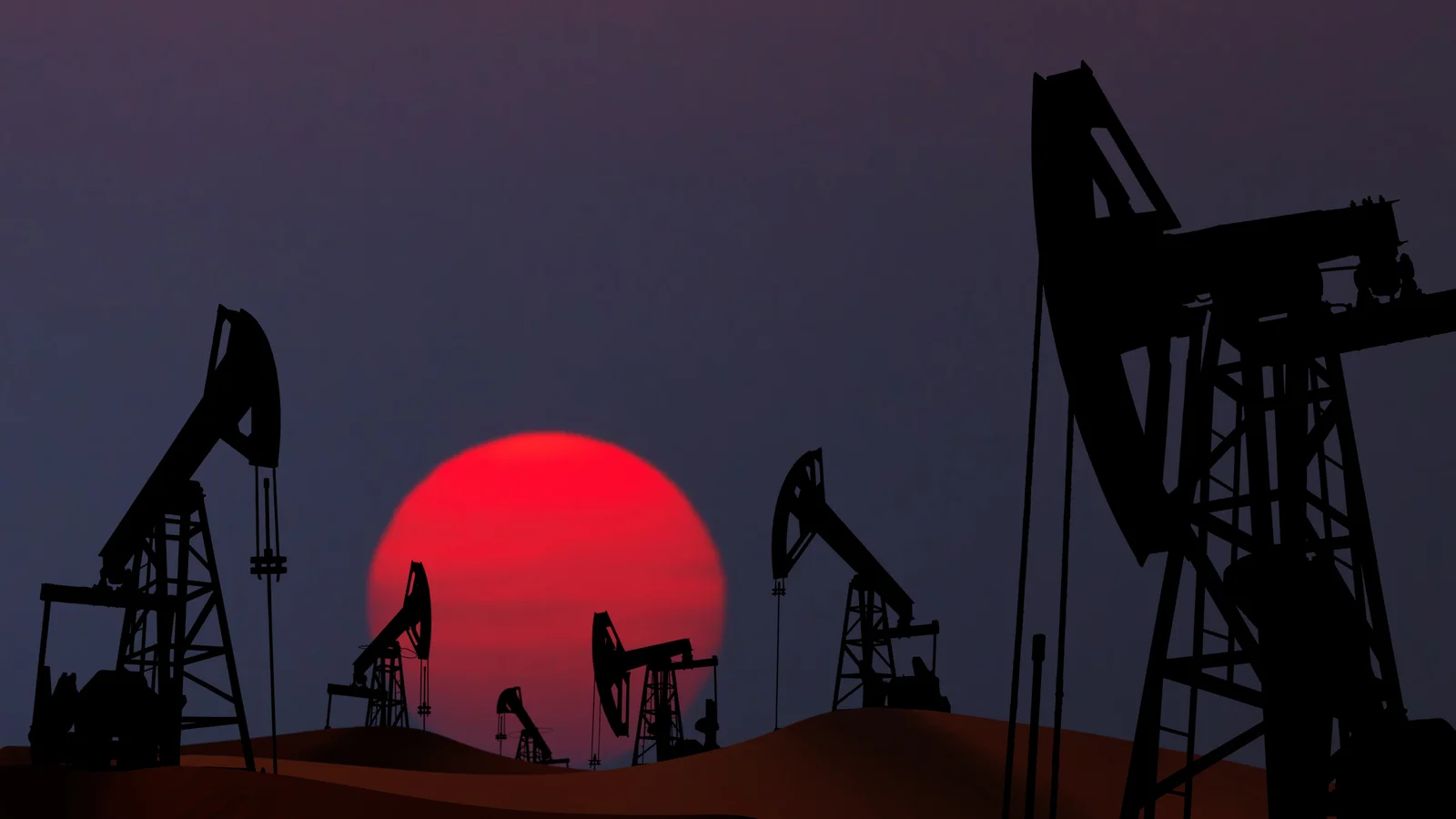 Silhouetted oil pumps against a large, vibrant red sunset, creating a stark contrast in the dusk sky.