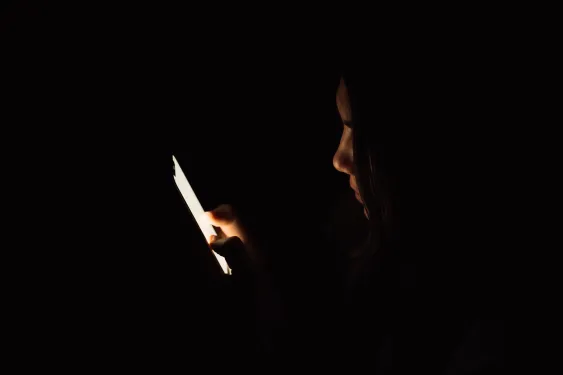 Lady looking at smartphone in dark room.