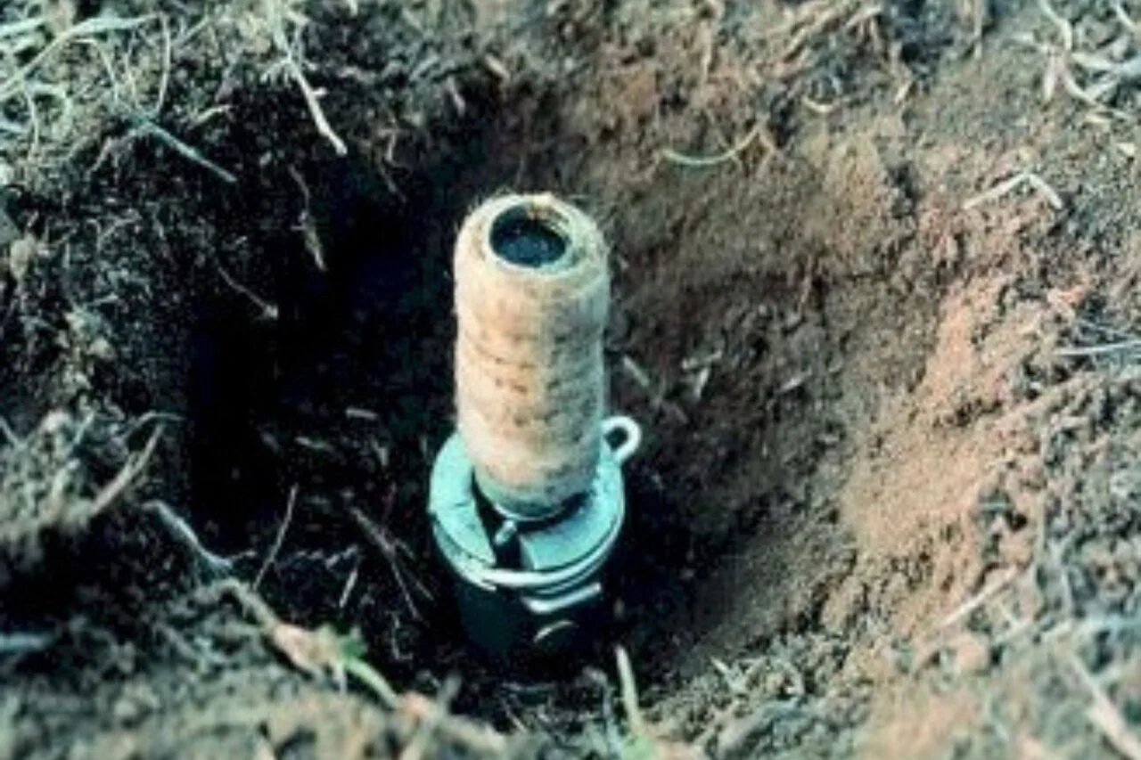 A close-up of an M-44 placed in a shallow hole in the dirt