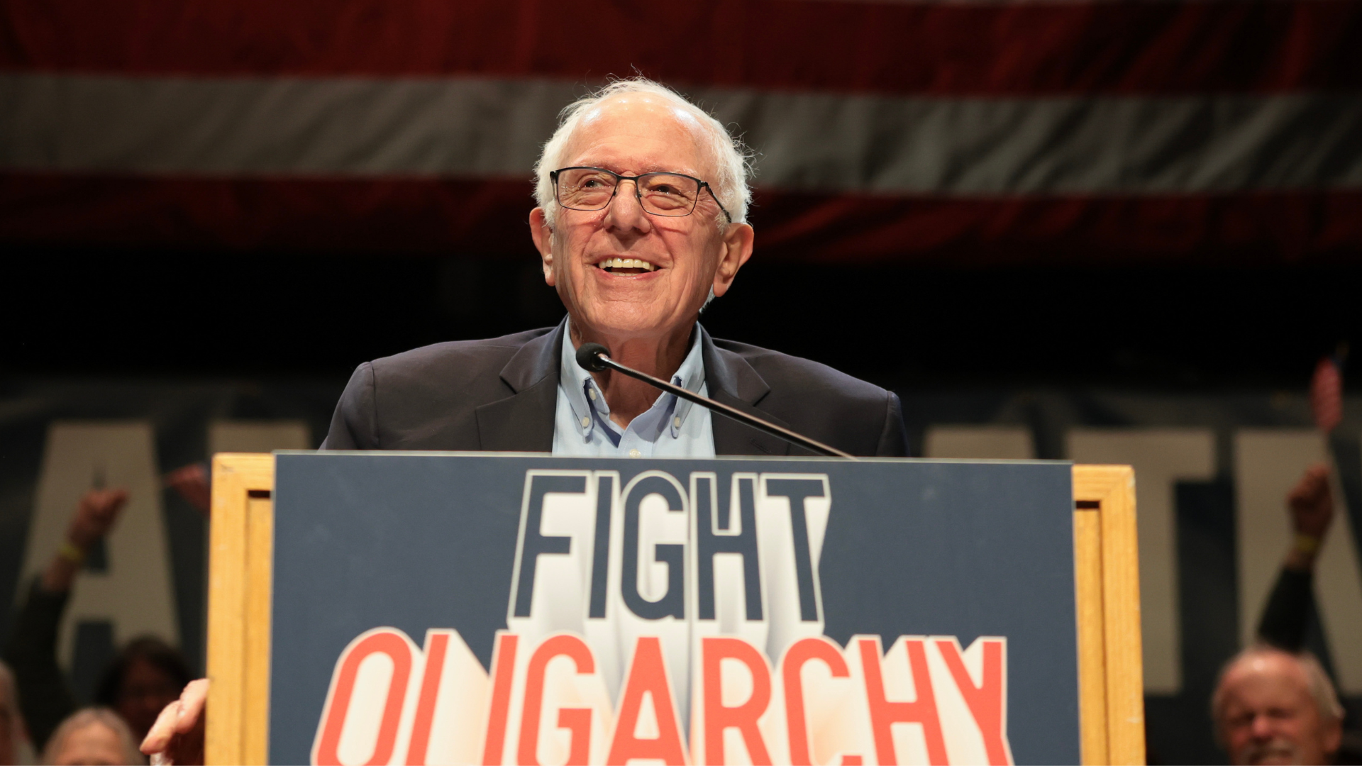 Bernie Sanders on a podium with a Fight Oligarchy sign