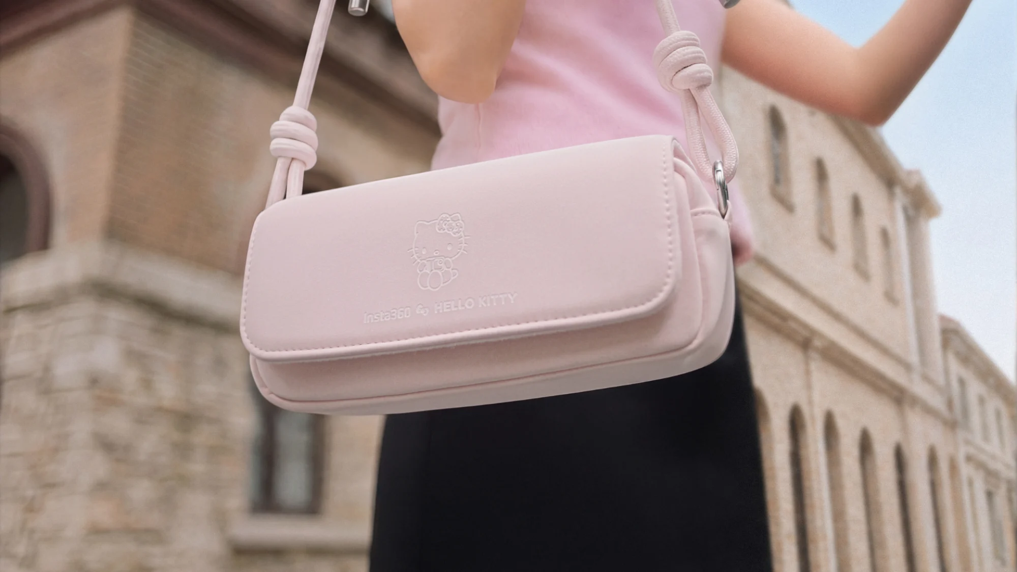 The Insta360 GO Ultra x Hello Kitty Limited Edition pink carry case on a woman's shoulder.