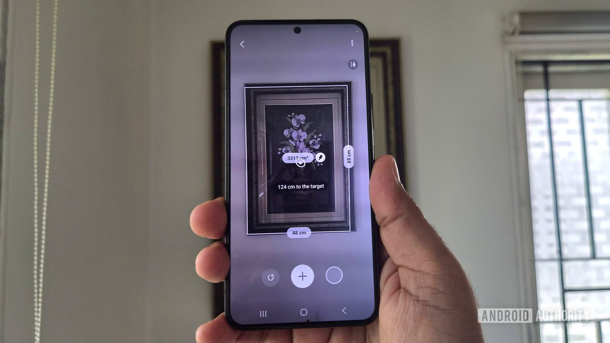 A Samsung phone in hand showing Quick Measure app