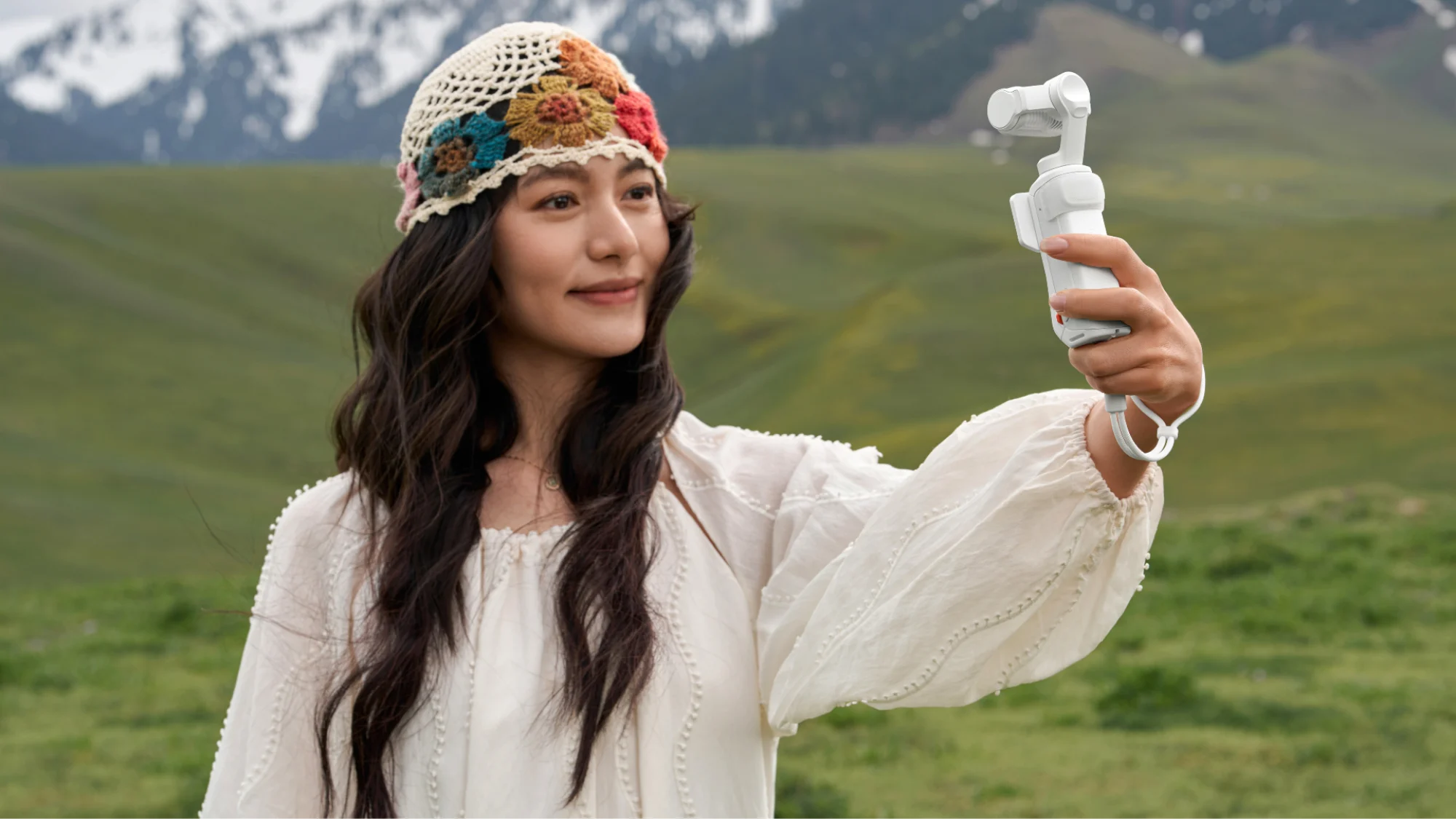 A woman holding up an Insta360 Luna Ultra to film herself.