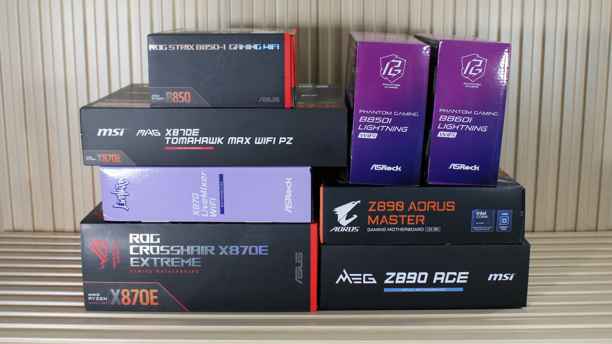 A collection of eight recent motherboards, in their boxes, on a desk, showcasing the types of boards that typically land on our lest of best motherboards we have benchmarked.