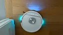 Shark UV Reveal 2-in-1 robot vacuum illuminating stain on hardwood floor near wall