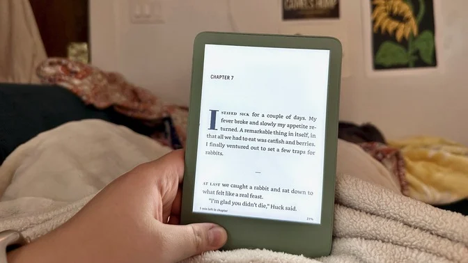 kindle e-reader held in lap with book on screen