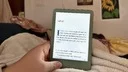 kindle e-reader held in lap with book on screen