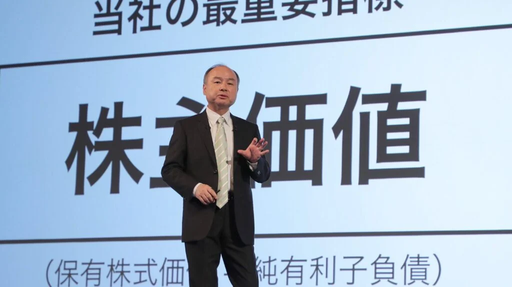 Masayoshi Son speaking in front of a screen with japanese writing