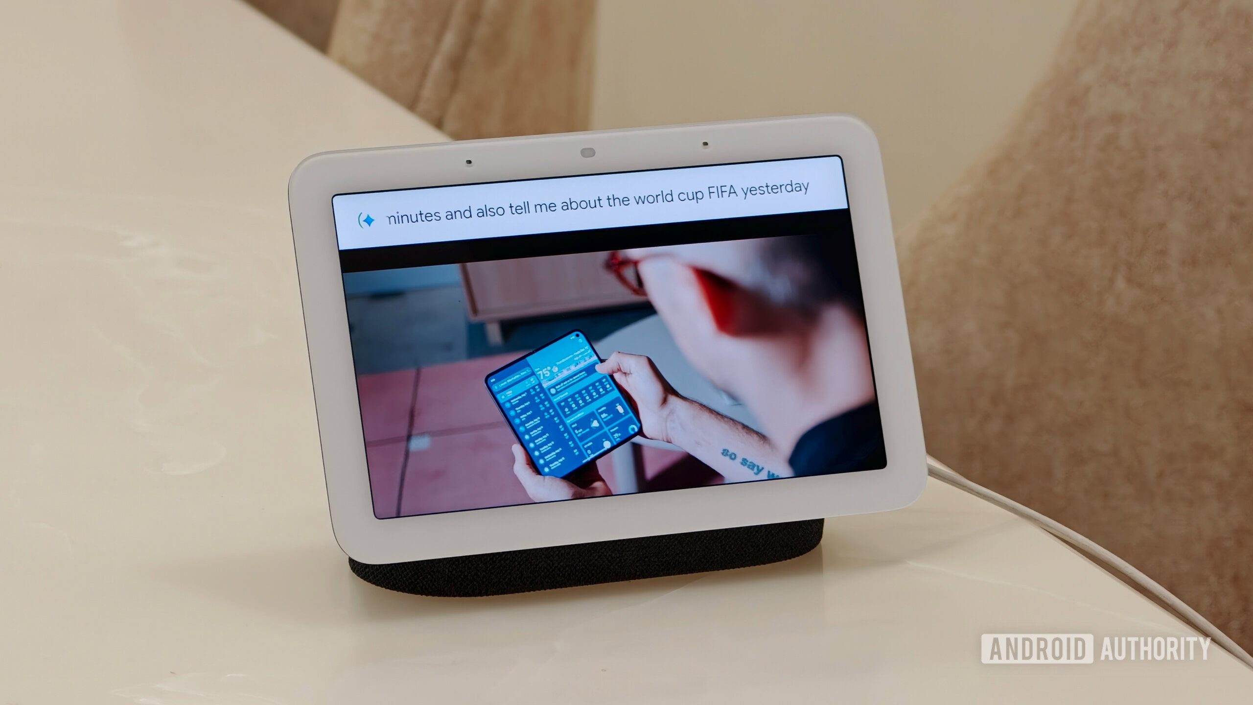 Google Nest Hub playing a YouTube video with a voice command text overlay at the top