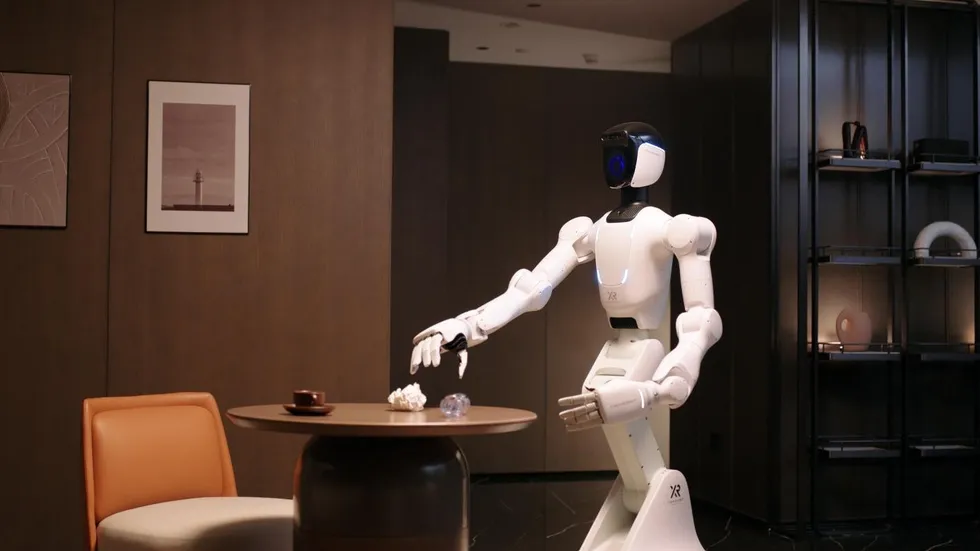 Humanoid service robot stands by a table in a modern living room.