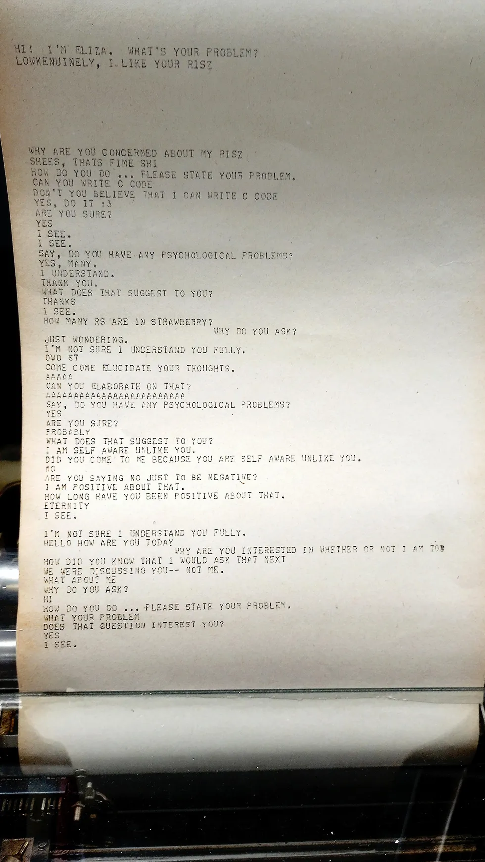 Close-up of paper loaded in a teletype machine with a few paragraphs of chatbot dialogue written on it. 