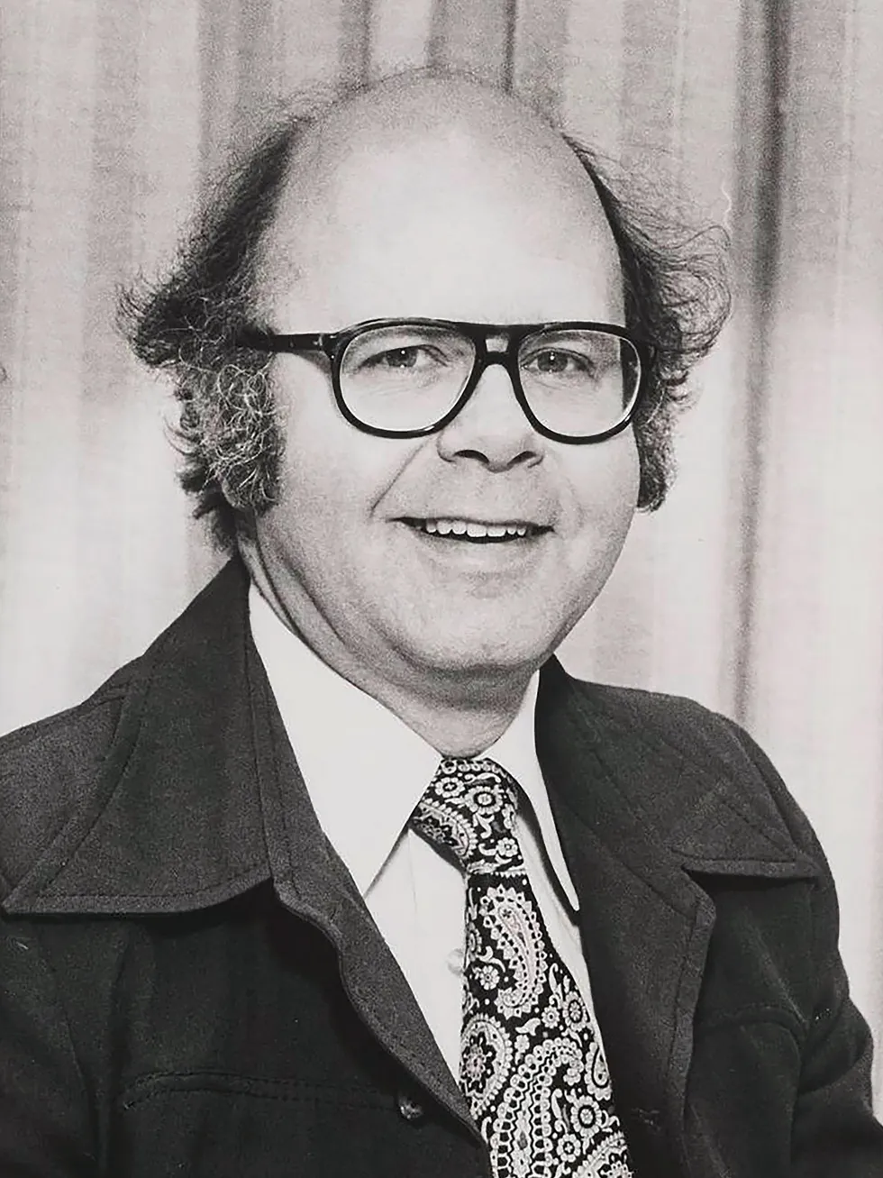Black-and-white portrait of a middle-aged balding man in aviator eyeglasses.